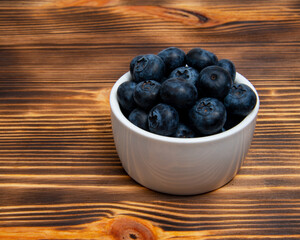 Fresh blueberry in white dish on wooden background