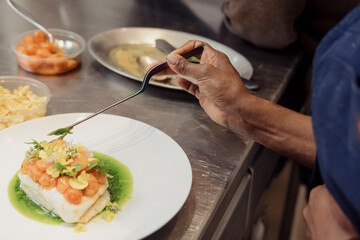 A female chef uses tweezer to plate a dish
