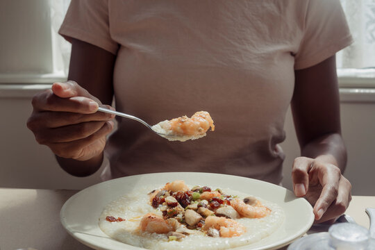 A person holding a spoon of shrimp and grits