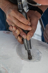 Hands of artist working the marble with a rotating tool