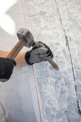 Detail of artist's hands sculpting marble with hammer and chisel
