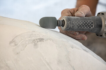 Hands of artist working the marble with a rotating tool