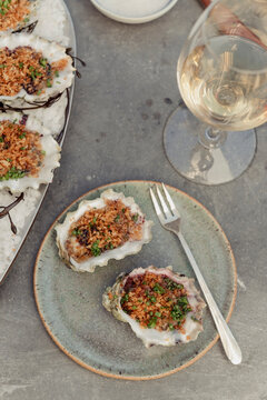 Grilled oysters and wine on gray surface
