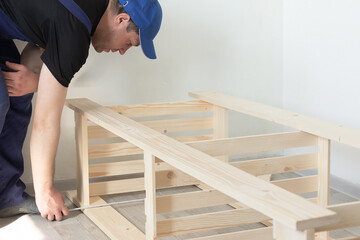 A carpenter measures a wooden structure. Carpentry work