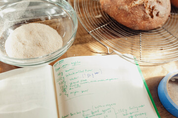 Still life of a bakers table with bread loaves, notebook, milled flour and bread dough
