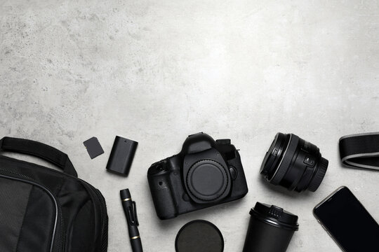 Professional photography equipment and backpack on grey stone table, flat lay. Space for text
