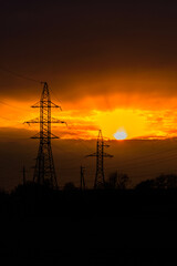 High voltage power line at sunset. Silhouettes of the metal pillars