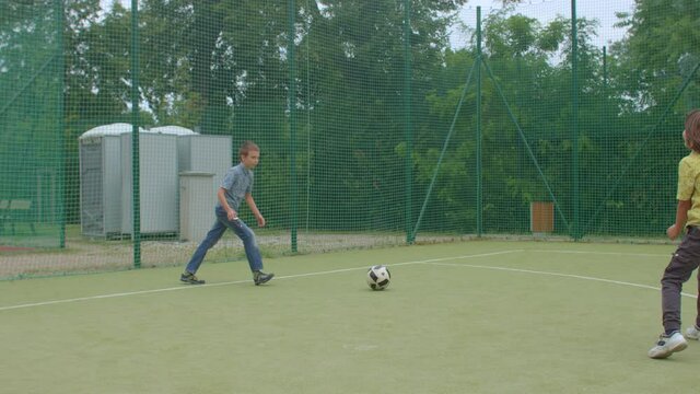 Two teenagers play ball on soccer field guy stops ball with his foot. Dexterity in body movement. Do a soccer jump kick.