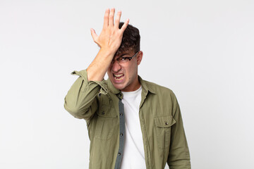 young handsome man raising palm to forehead thinking oops, after making a stupid mistake or...