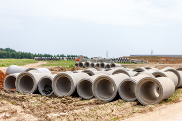 Concrete pipes for the construction of objects lie on the ground.