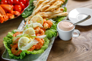 A dish of lettuce leaves, lemon and king prawns.