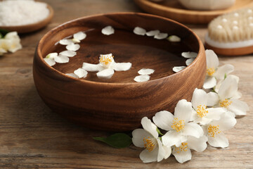 Obraz na płótnie Canvas Bowl with water and beautiful jasmine flowers on wooden table