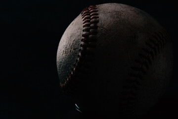 Dark moody baseball close up on black background.
