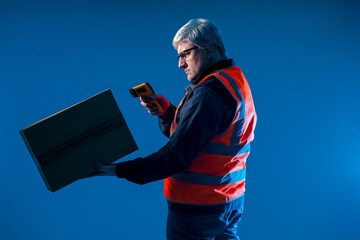 A warehouse worker holds a device for reading information. Warehouse worker on a blue background. A...