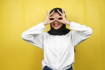Naklejka premium Beautiful asian young muslim woman smiling cheerfully and excitedly, with glasses hands, isolated on yellow background