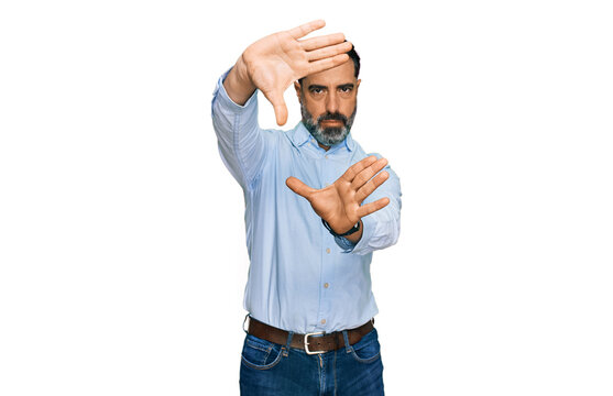 Middle aged man with beard wearing business shirt doing frame using hands palms and fingers, camera perspective