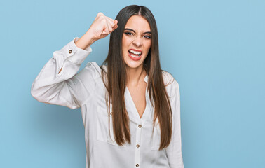 Young beautiful woman wearing casual white shirt angry and mad raising fist frustrated and furious while shouting with anger. rage and aggressive concept.