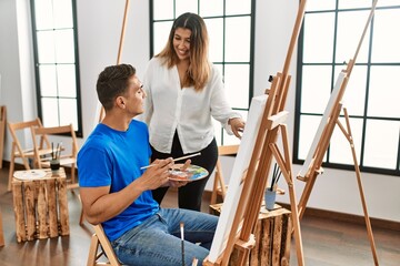 Student and teacher smiling happy painting at art school.