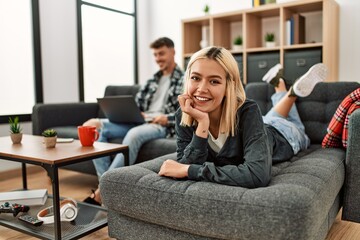 Young caucasian couple smiling happy using laptop sitting on the sofa at home.