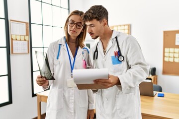 Two hispanic doctor working in a medical meeting looking bone scan at the clinic office.