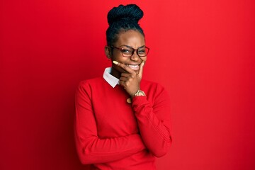 Young african american woman wearing casual clothes and glasses looking confident at the camera smiling with crossed arms and hand raised on chin. thinking positive.