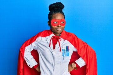 Young african american woman wearing doctor uniform and super hero costume smiling looking to the side and staring away thinking.