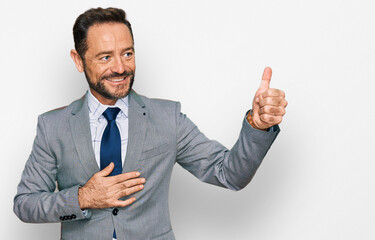 Middle age man wearing business clothes looking proud, smiling doing thumbs up gesture to the side