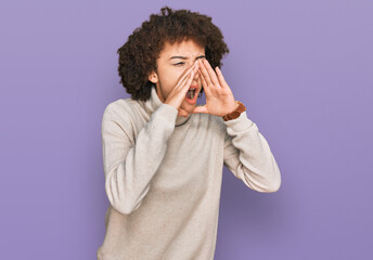 Young hispanic girl wearing wool winter sweater shouting angry out loud with hands over mouth