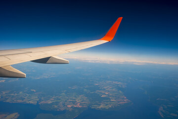 Fototapeta na wymiar Classic image through aircraft window onto wing. Flight view over Russia