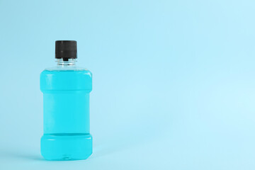 Mouthwash on light blue background, space for text