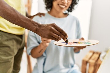 African american artist couple smiling happy painting at art studio.