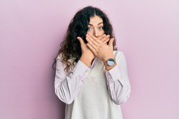 Young brunette woman with curly hair wearing casual clothes shocked covering mouth with hands for mistake. secret concept.