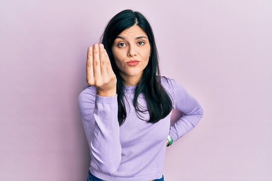 Young hispanic woman wearing casual clothes doing italian gesture with hand and fingers confident expression
