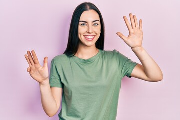 Beautiful woman with blue eyes wearing casual t shirt showing and pointing up with fingers number...