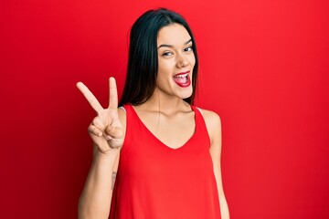 Young hispanic girl wearing casual style with sleeveless shirt showing and pointing up with fingers...