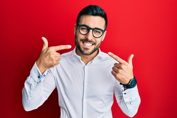 Young hispanic businessman wearing shirt and glasses smiling cheerful showing and pointing with...
