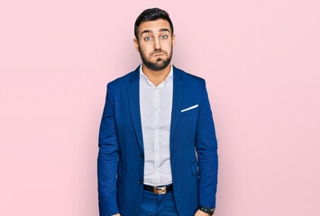 Young hispanic man wearing business jacket puffing cheeks with funny face. mouth inflated with air, crazy expression.