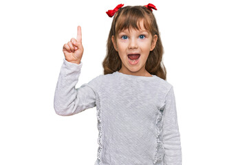 Little caucasian girl kid wearing casual clothes pointing finger up with successful idea. exited...
