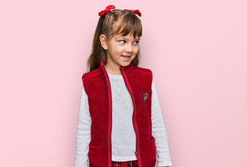 Little caucasian girl kid wearing casual clothes looking away to side with smile on face, natural expression. laughing confident.