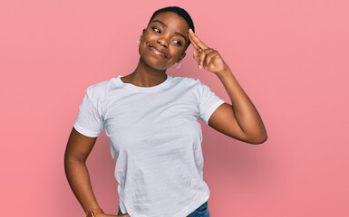Young african american woman wearing casual white t shirt smiling pointing to head with one finger, great idea or thought, good memory