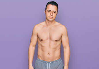 Fototapeta premium Handsome young man wearing swimwear shirtless looking sleepy and tired, exhausted for fatigue and hangover, lazy eyes in the morning.