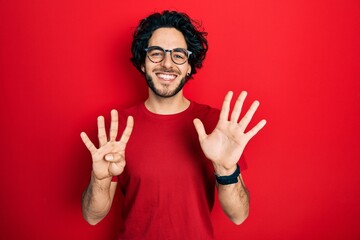 Handsome hispanic man wearing casual t shirt and glasses showing and pointing up with fingers...