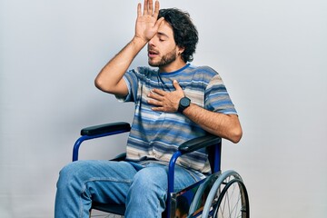 Handsome hispanic man sitting on wheelchair touching forehead for illness and fever, flu and cold,...