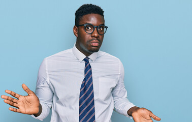 Handsome business black man wearing white shirt and tie clueless and confused expression with arms...