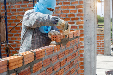 masonry worker make concrete wall by cement block and plaster at construction site