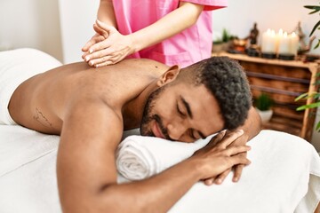 Fototapeta na wymiar Young african american smiling happy reciving back massage at beauty center.