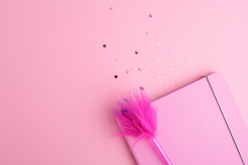 Pink background, flat lay style. Sparkles and note book with funny pen on pink trendy background.