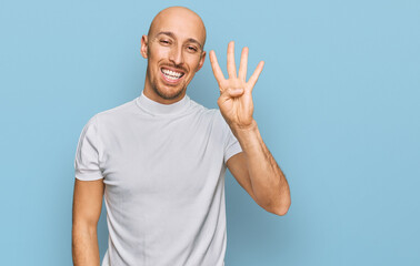 Bald man with beard wearing casual white t shirt showing and pointing up with fingers number four while smiling confident and happy.