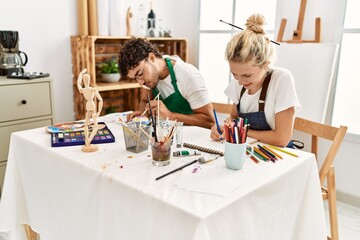 Young artist couple smiling happy painting at art studio.
