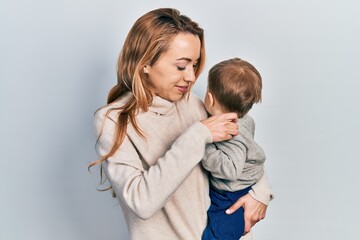 Young caucasian woman holding and hugging her son with love. Family of two bonding together. Mother holding infant toddler